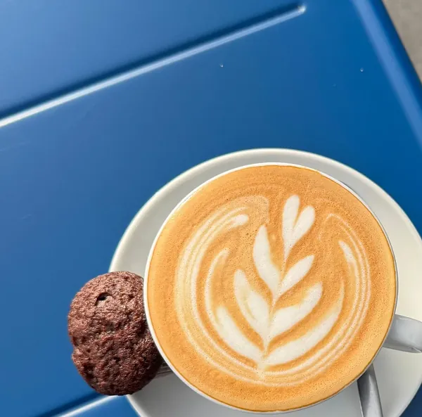 Cappuccino met een koek op een blauw tafeltje