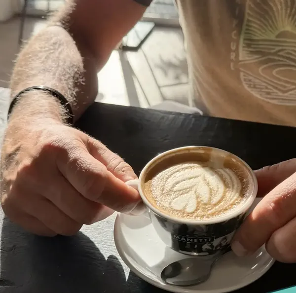 Een cappuccino in twee handen aan de bar